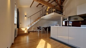 Una cocina amplia con piso de madera, una isla moderna y una escalera que lleva a un nivel superior.