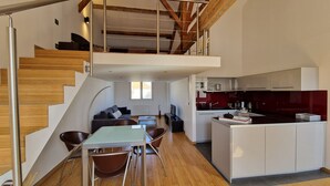 Un loft moderno con escalera de madera, zona de comedor, cocina y salón.