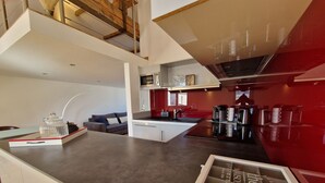 Una cocina moderna con una isla central, un área de comedor con un sofá y una pared de acento roja.
