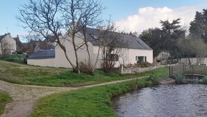 A riverside path leading to a white building with a sloped roof, surrounded by greenery and trees. - Charming Breton Cottage Near Beaches and Salt Marshes, Wi-Fi, Pet-Friendly, Bikes Available (Assérac)