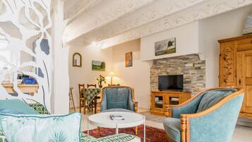 Un salon comprenant un canapé, des fauteuils, une table basse, un téléviseur et une cheminée.