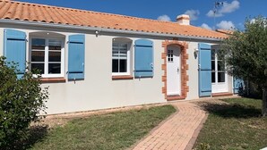 Ein zweistöckiges Haus mit rotem Ziegeldach, blauen Fensterläden und einer Ziegelveranda.