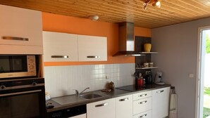 Eine moderne Küche mit weißen Schränken, einer schwarzen Arbeitsplatte und einer Holzbalkendecke.