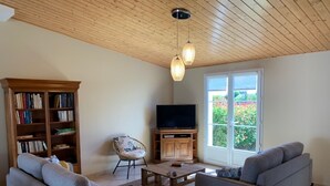 Ein Wohnzimmer mit Holzboden, einem Fernseher, einem Bücherregal und zwei Sofas.