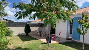 Ein Garten mit Terrasse, kleinem Tisch und Stühlen.