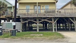 A two-story building with a wooden deck and a sign for a business.