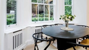 A dining area with a round table, black chairs, and a vase of flowers. - Classy 2BR 2BA in the ♥️ of Central London ❄️ Air Con. 🌿 Terrace | Sleeps 6 (Greater London)