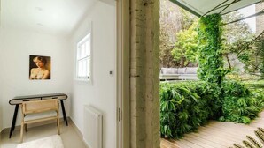 A room with a white radiator, a framed picture on the wall, a small wooden bench, and a white rug. - Classy 2BR 2BA in the ♥️ of Central London ❄️ Air Con. 🌿 Terrace | Sleeps 6 (Greater London)