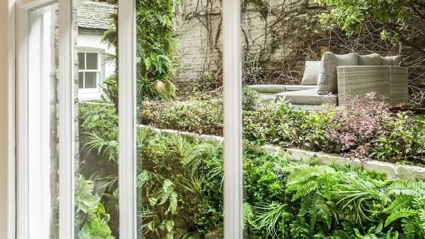 A lush garden with a variety of plants and a cozy seating area with cushions. - Classy 2BR 2BA in the ♥️ of Central London ❄️ Air Con. 🌿 Terrace | Sleeps 6 (Greater London)