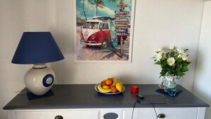 A room with a desk, a lamp, a fruit bowl, a vase with flowers, and a wall poster. - One-bedroom apartment with terrace, AC and parking in Capbreton (Capbreton)