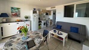 A compact living space with a kitchenette, a dining area with a patterned table, a sofa, and a single chair. - One-bedroom apartment with terrace, AC and parking in Capbreton (Capbreton)