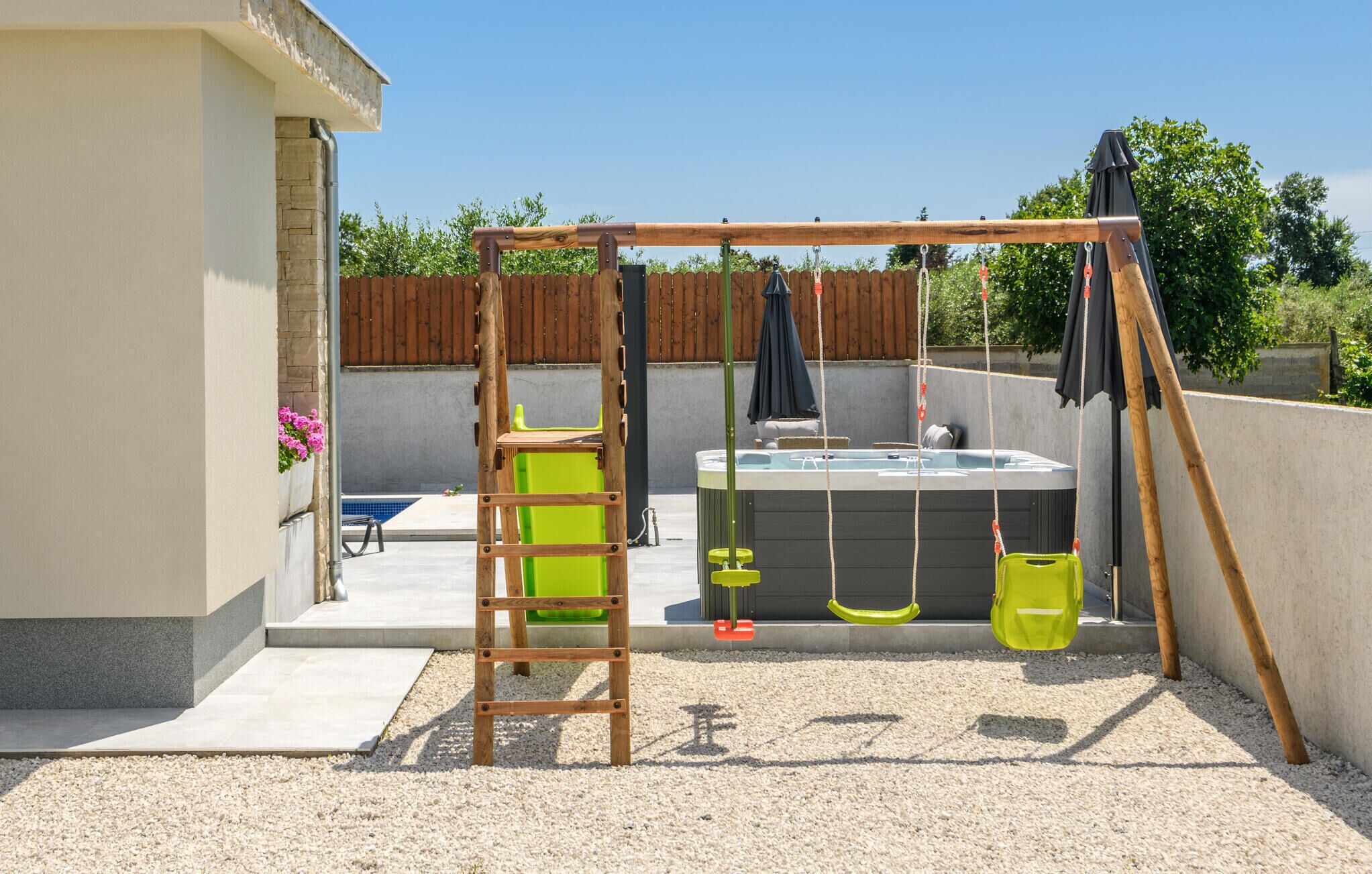 Un jardin avec une balançoire en bois, un jacuzzi et une échelle.