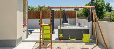 Un jardin avec une balançoire en bois, un jacuzzi et une échelle.