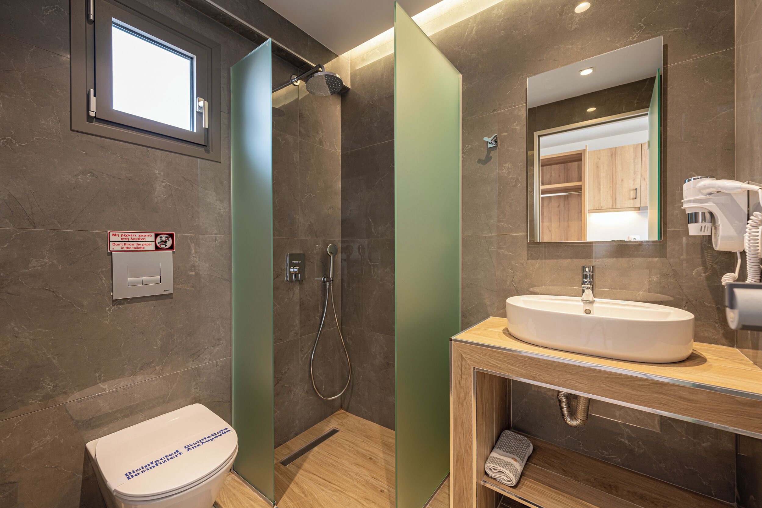 A modern bathroom with a shower, toilet, sink, and a mirror.