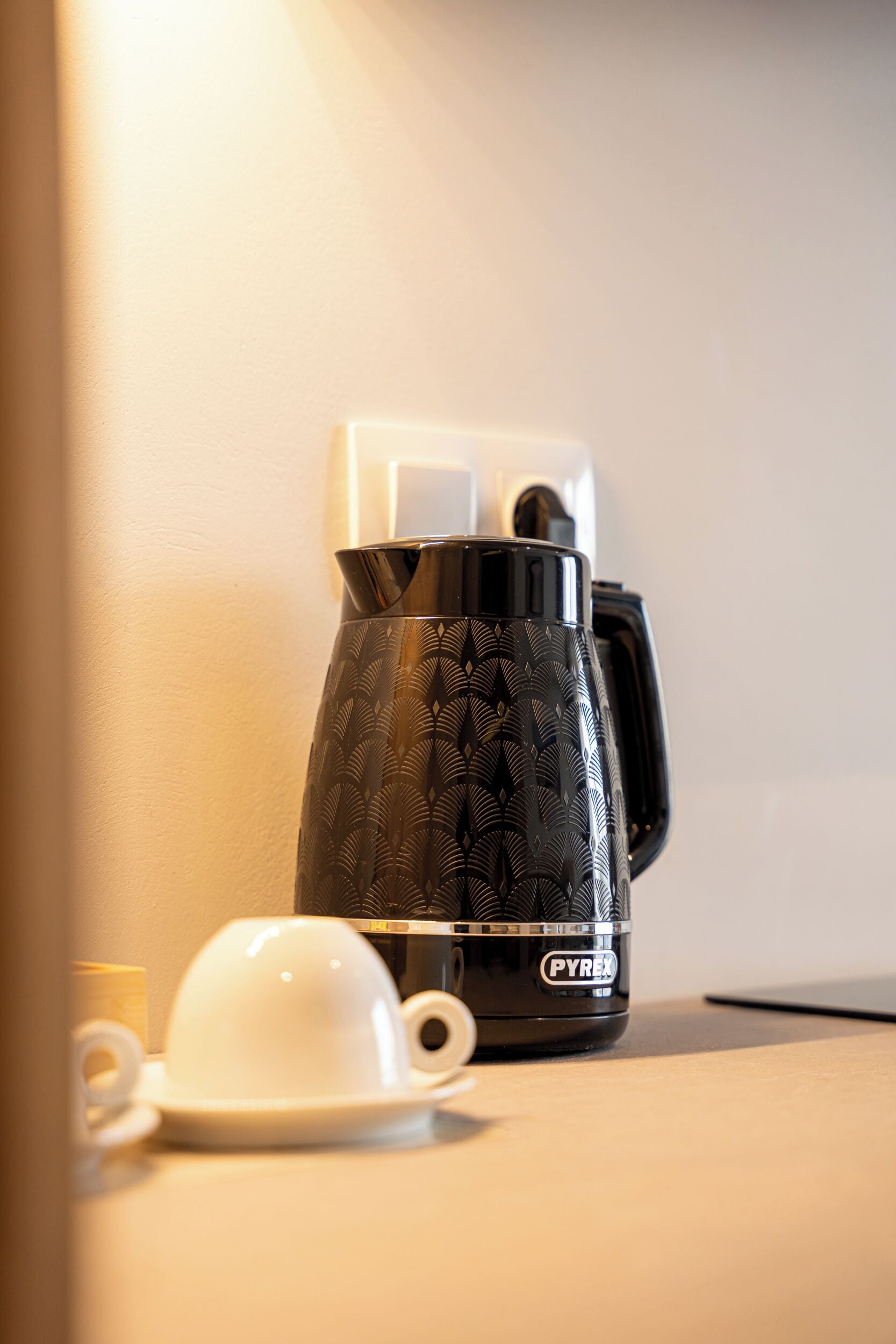 A black coffee maker with a white cup and saucer on a table.