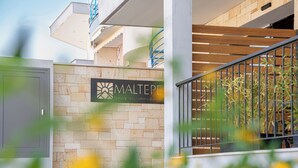 Un edificio con un letrero que dice 'MALTEPE alojamiento de lujo', una pared de ladrillo, una escalera de madera y una barandilla de metal.