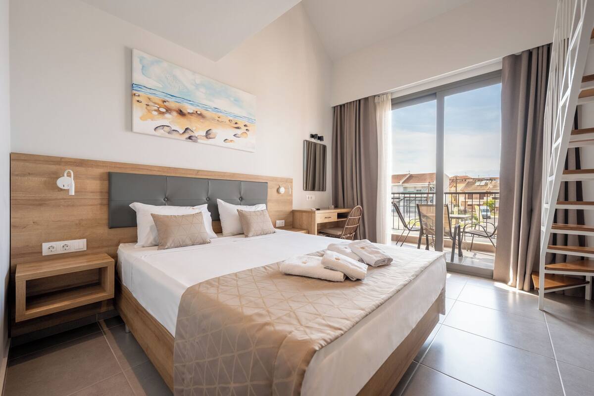Una habitación de hotel con una cama grande, un escritorio, una silla y un balcón con vistas.