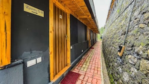 A corridor with wooden doors marked "Rooms 5-8" leading to a stone wall. - Stoneshed Resort And Hotel (Nainital)