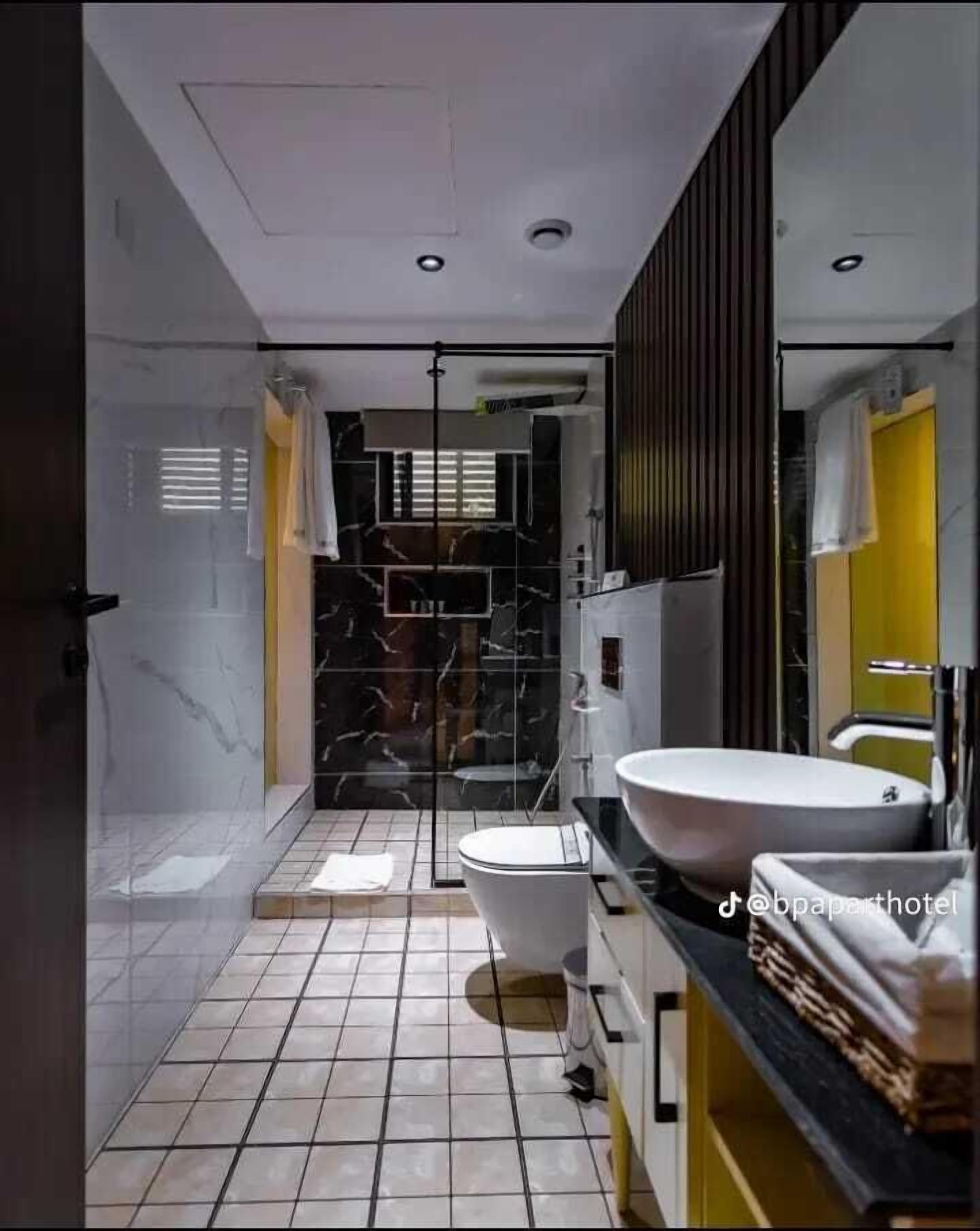 Ein modernes Badezimmer mit Duschkabine aus Glas, einer weißen Toilette, einem großzügigen Waschbecken und einem Spiegel.