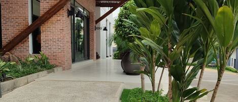 A building with a brick facade, a covered walkway, and a landscaped area with plants and a pebble border.