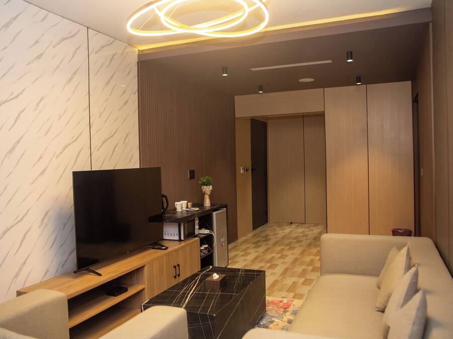 Una sala de estar moderna con una televisión de pantalla plana, una mesa de centro, un sofá y un armario.
