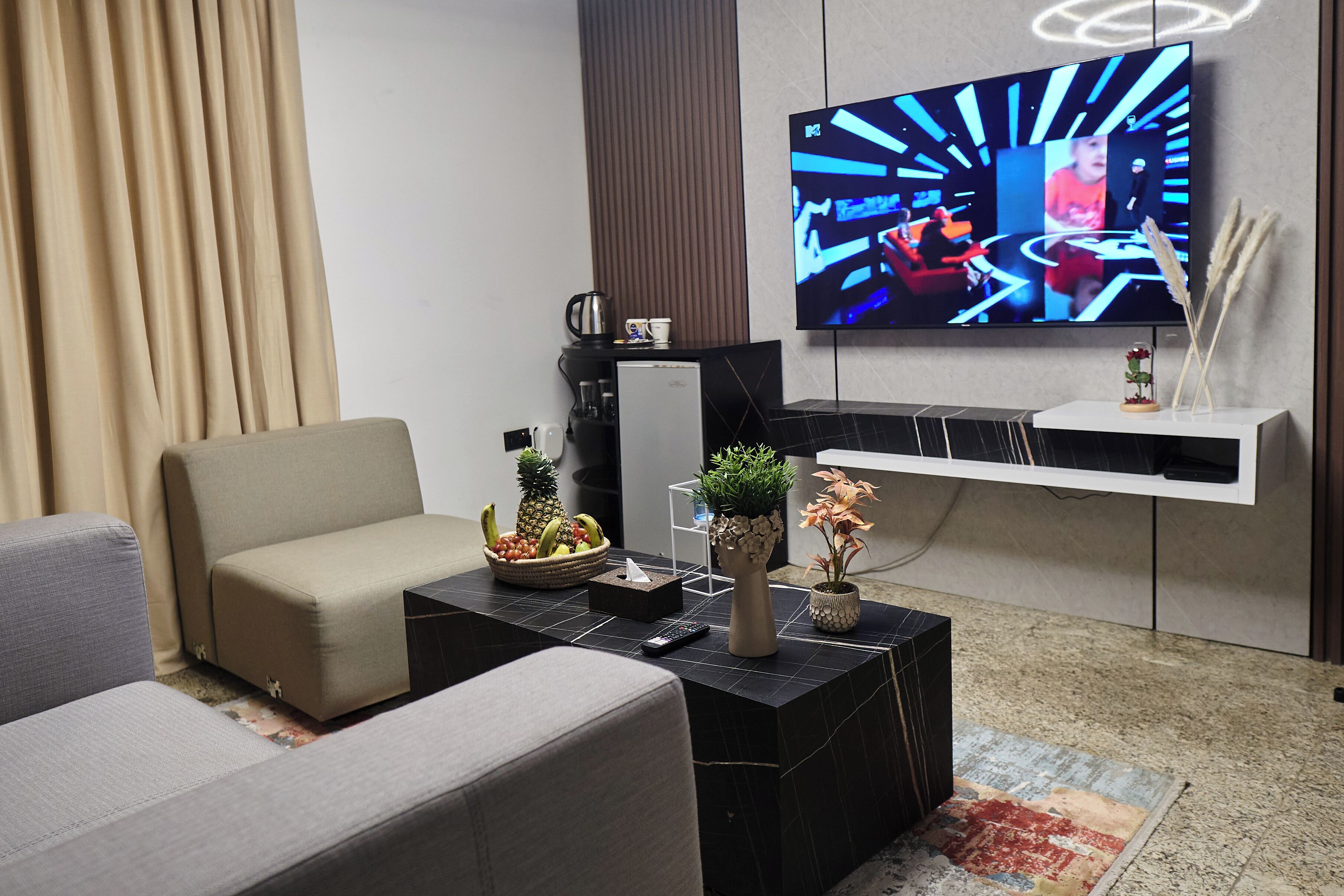 Een moderne woonkamer met een bank, salontafel en een flatscreen televisie aan de wand.