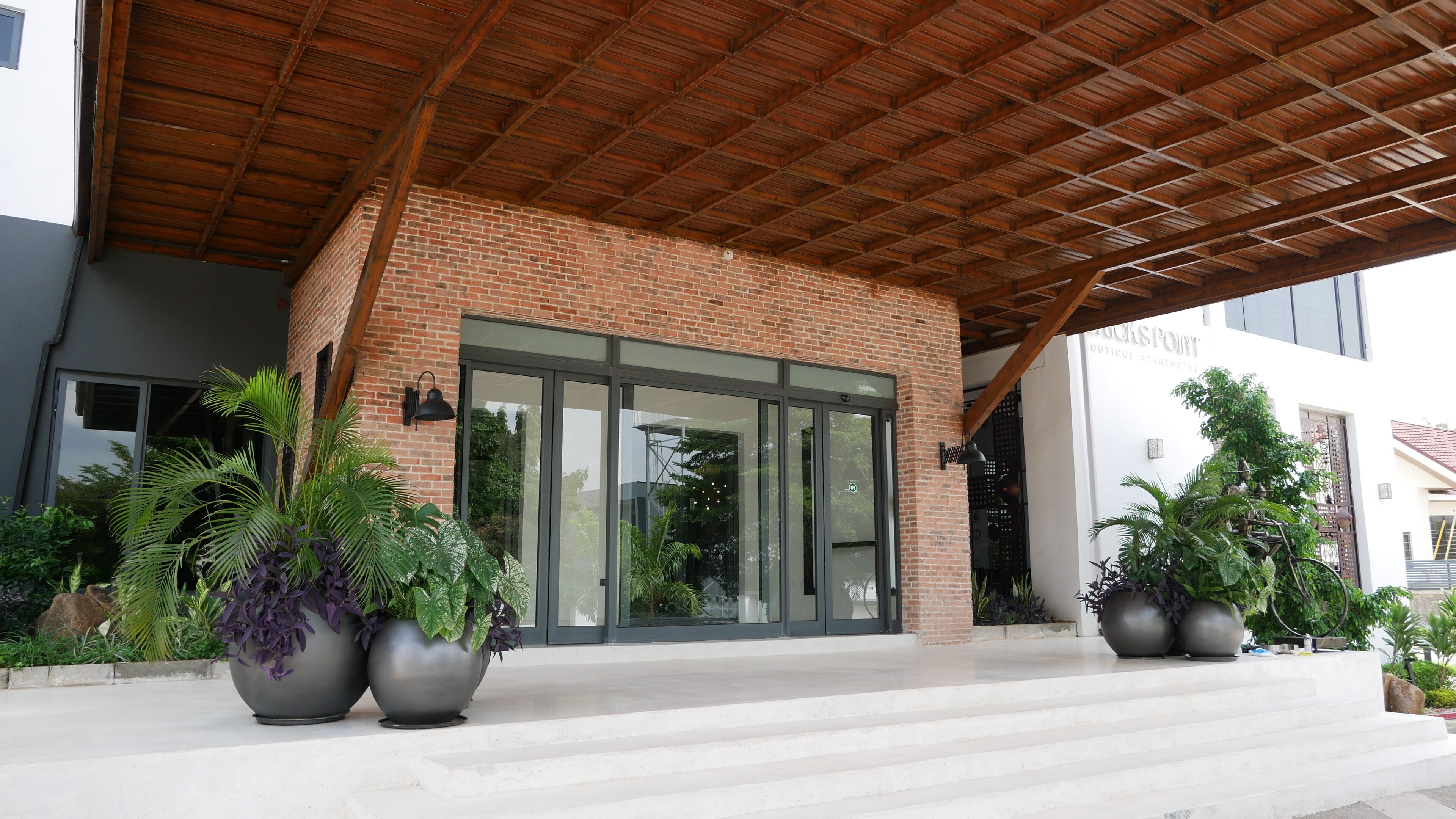 A modern building with a brick facade, large glass doors, and a covered entrance area.