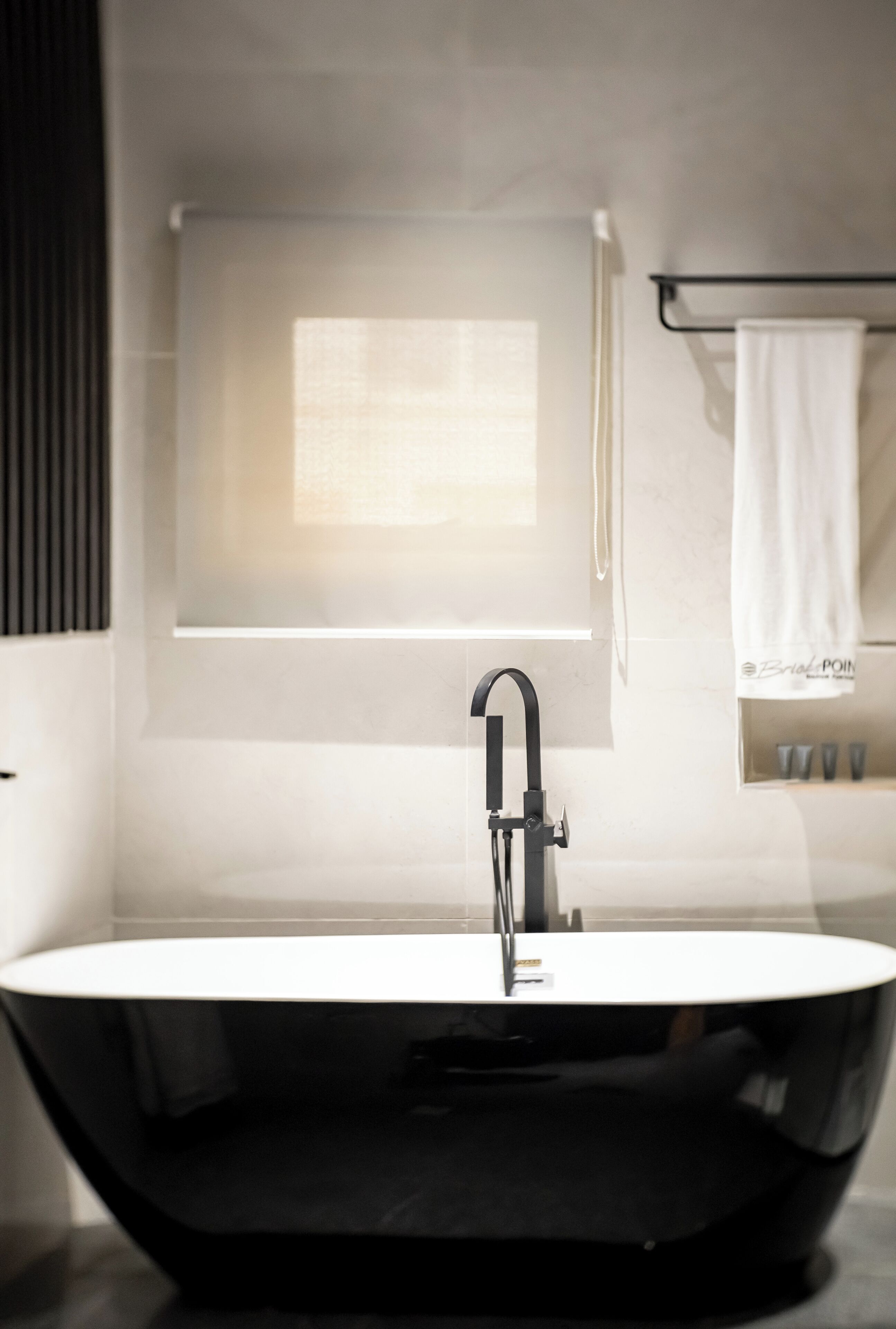 A modern bathroom with a freestanding bathtub, a towel rack with a white towel, and a window with a view.