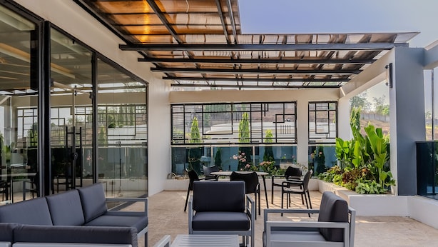 An outdoor patio area with modern furniture, glass doors, and a view of the surrounding landscape. - BRICKSPOINT BOUTIQUE APARTHOTEL ASOKORO (Abuja)