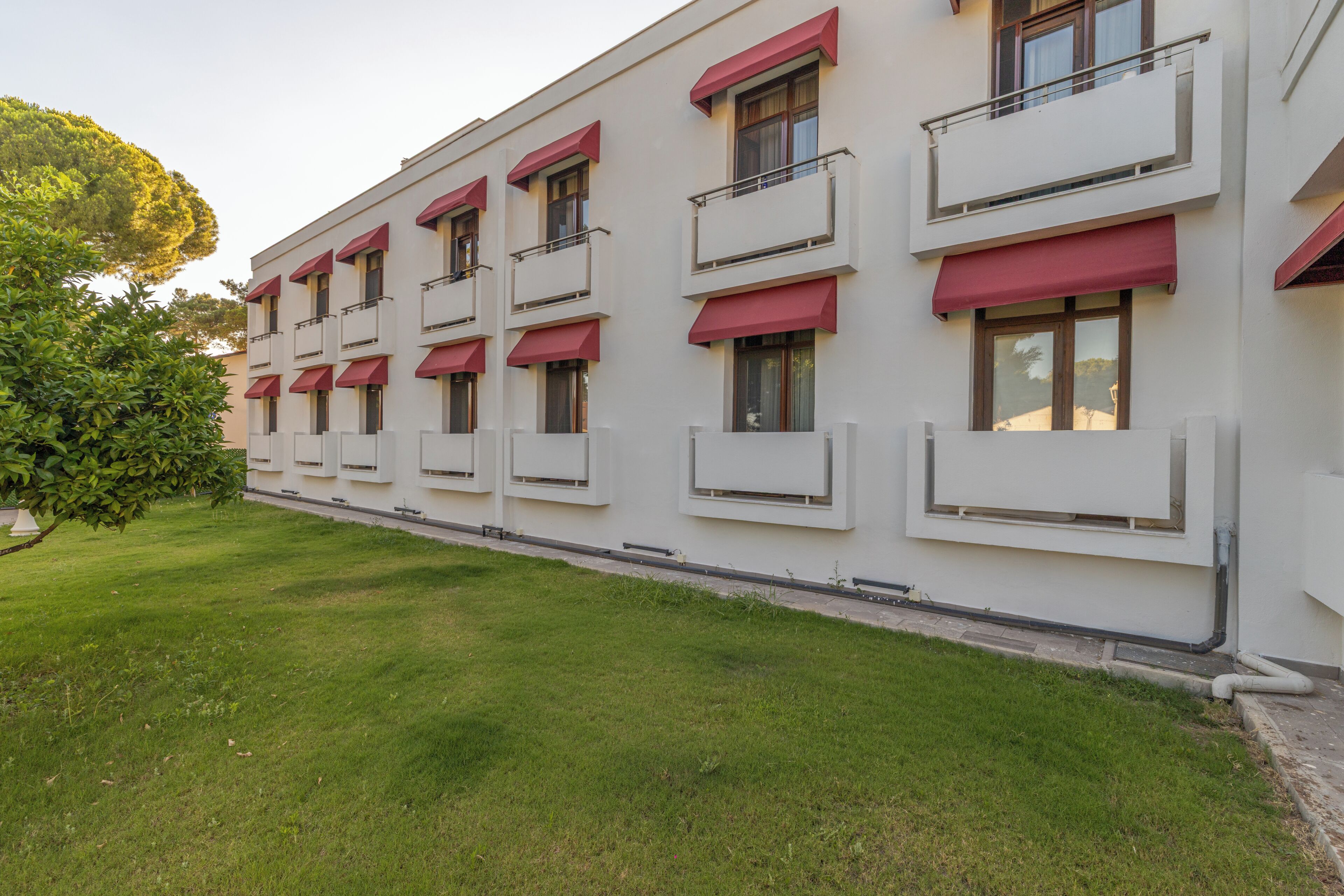 Un edificio de varios pisos con balcones y toldos, rodeado de un césped bien cuidado.