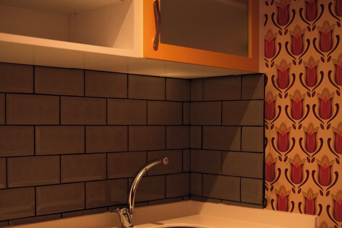 Une cuisine équipée d’un évier, de meubles en bois et d’un mur décoré d’un motif.
