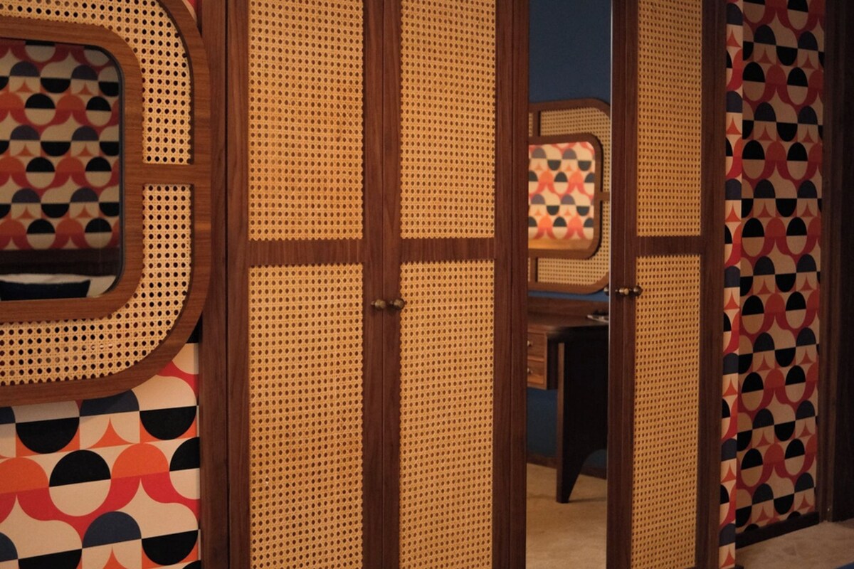 Een kamer met een bed, een spiegel en een inloopkast met een geometrisch patroon.