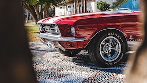 A vintage red car parked on a cobblestone street with trees and a building in the background. - 74 Hotel (Antalya)