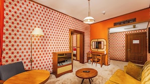 A room with patterned wallpaper, a wooden table, a sofa, a lamp, and a television. - 74 Hotel (Antalya)