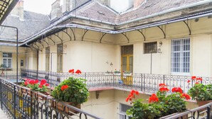 A courtyard with a balcony, potted plants, and a yellow door. - Lovely Apartment by National Museum (Budapest)