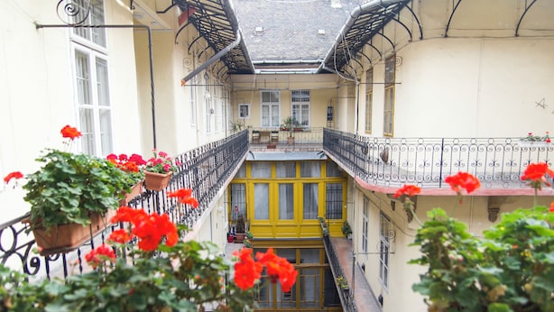 A multi-level courtyard with balconies, potted plants, and a yellow door. - Lovely Apartment by National Museum (Budapest)