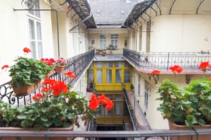 Un patio de varios niveles con balcones, plantas en macetas y una puerta amarilla.