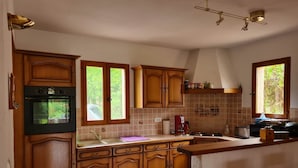 A kitchen with wooden cabinets, a built-in oven, a sink, and a window with a view of greenery.