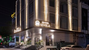 Un hotel moderno con un letrero llamativo, amplias ventanas y un área de entrada pavimentada.