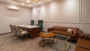 Una sala de conferencias con un escritorio de madera, sillas de cuero, un sofá marrón y una mesa de centro de vidrio.