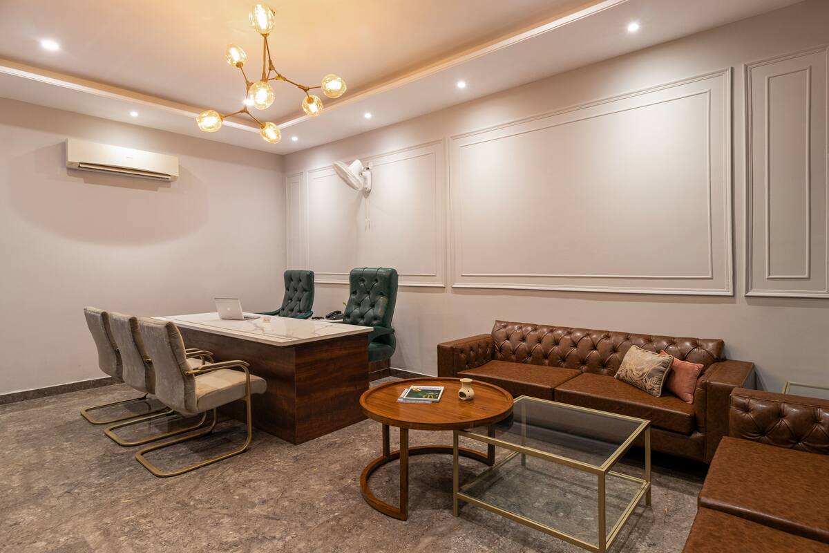 A conference room with a wooden desk, leather chairs, a brown sofa, and a glass coffee table.