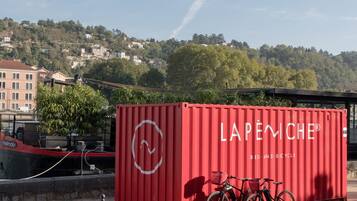 A red shipping container with the text "LAPENICHE® BED AND BICYCLE" and a bicycle parked in front.