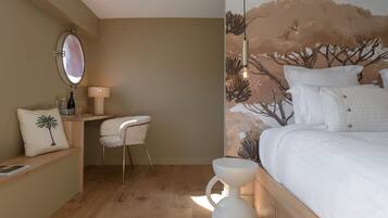 A bedroom with a bed, a bedside table, a chair, a mirror, and a wall mural.