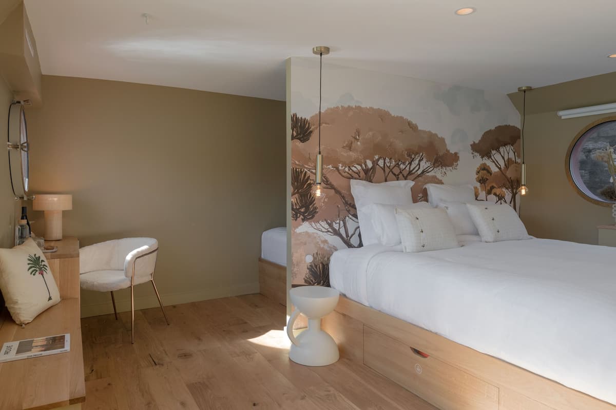 Une chambre à coucher avec un grand lit, une chaise, une table de chevet et une fresque murale.