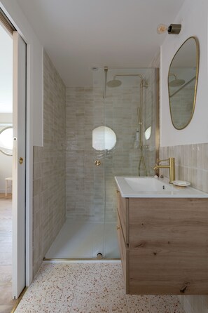 A modern bathroom with a glass-enclosed shower, a wooden vanity, and a large mirror.