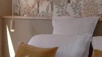 A bedroom with a bed, white and brown pillows, and a wall with a floral pattern.