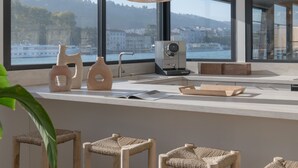 Een moderne keuken met grote ramen, houten krukken en uitzicht op een waterpartij.