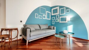 Ein Wohnzimmer mit einer Couch, einem kleinen runden Tisch und einer Lampe.