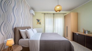 A neatly arranged bedroom with a bed, bedside table, lamp, wardrobe, and a hanging light fixture.