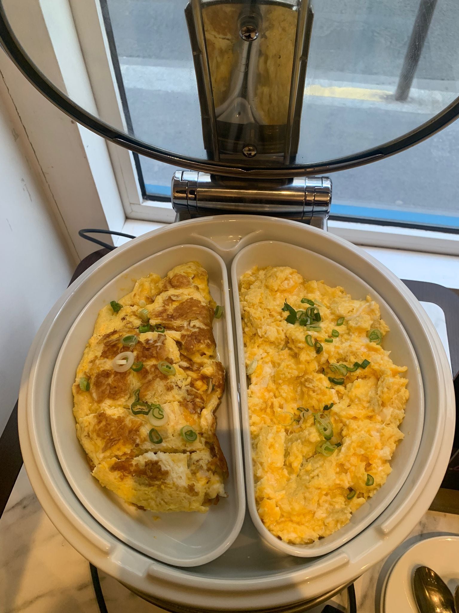 A breakfast dish with scrambled eggs and a baked omelette in a white ceramic dish.